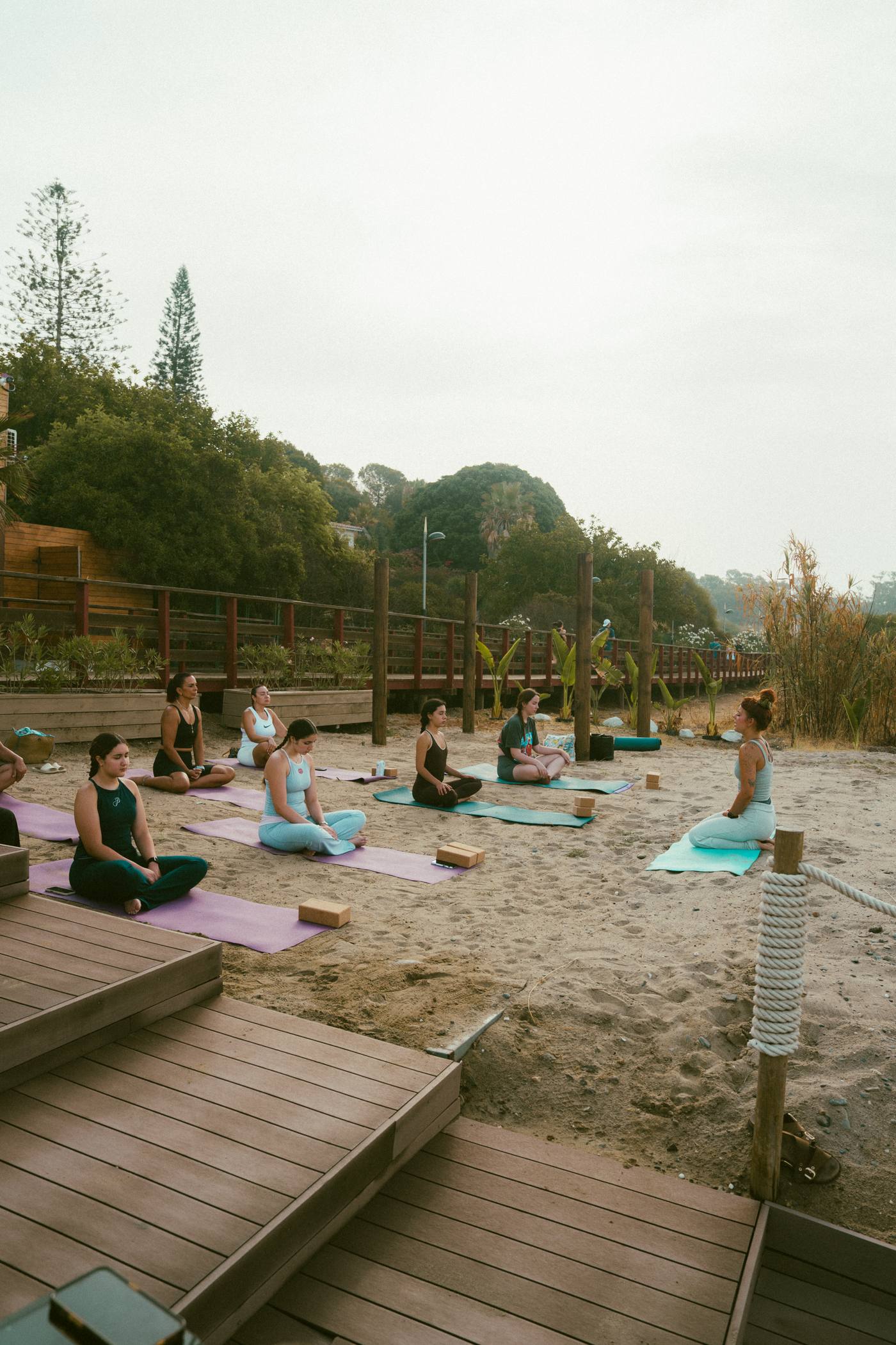 Group seated in a circle during a beach yoga session in Marbella